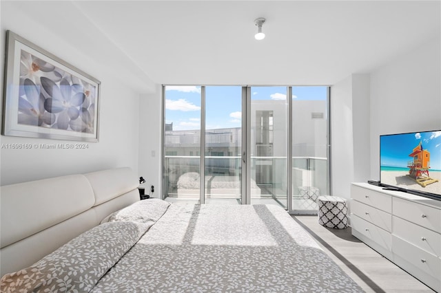 bedroom featuring light hardwood / wood-style floors, a wall of windows, and access to outside