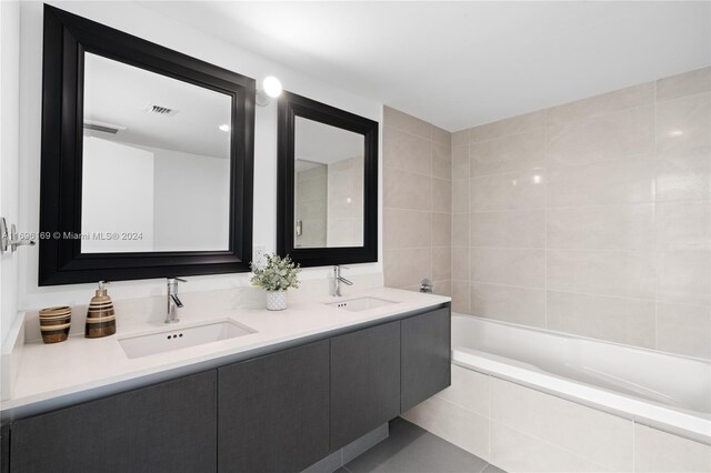 bathroom with tiled bath, vanity, and tile walls