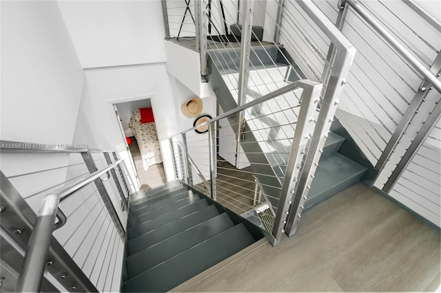 staircase with wood-type flooring and a towering ceiling