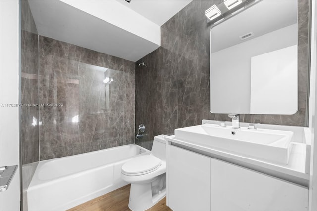 full bathroom with vanity, tiled shower / bath combo, toilet, tile walls, and wood-type flooring