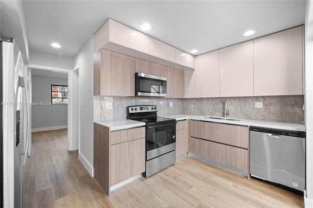 kitchen with sink, stainless steel appliances, tasteful backsplash, light hardwood / wood-style floors, and light brown cabinetry