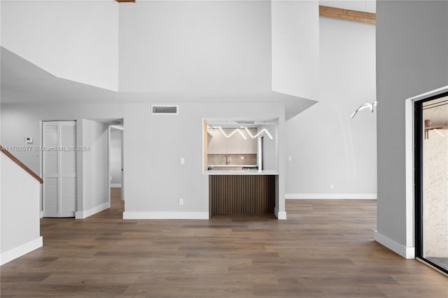 unfurnished living room featuring wood-type flooring and a high ceiling