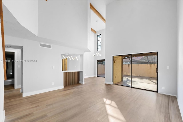 unfurnished living room with light hardwood / wood-style flooring and a high ceiling