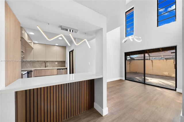 kitchen featuring kitchen peninsula, light wood-type flooring, backsplash, stainless steel appliances, and sink