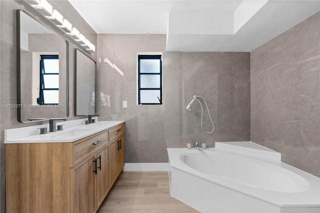 bathroom featuring vanity, wood-type flooring, tile walls, and a tub