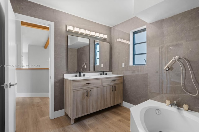 bathroom featuring wood-type flooring, vanity, tile walls, and a tub