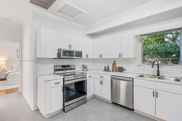 kitchen with appliances with stainless steel finishes, tasteful backsplash, white cabinetry, and sink