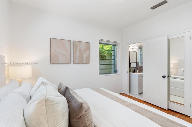 bedroom featuring light wood-type flooring and connected bathroom