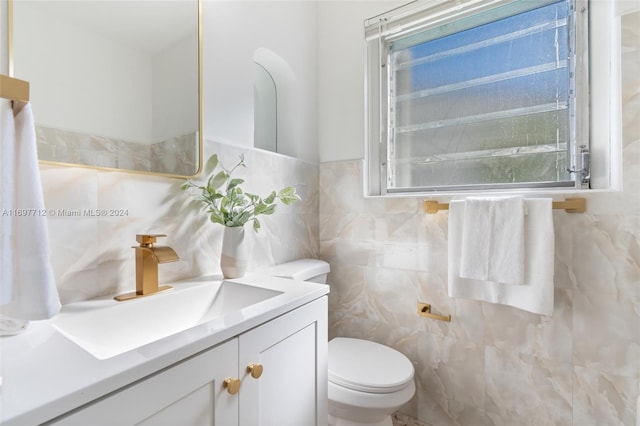 bathroom featuring vanity, toilet, and tile walls