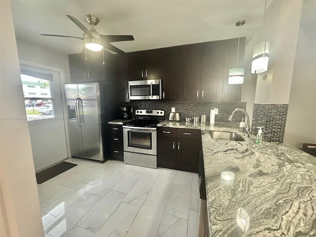 kitchen featuring light stone countertops, appliances with stainless steel finishes, tasteful backsplash, decorative light fixtures, and kitchen peninsula