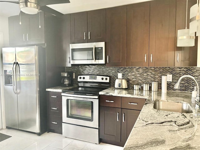 kitchen featuring light stone countertops, tasteful backsplash, stainless steel appliances, ceiling fan, and sink