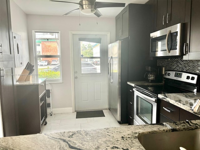 kitchen featuring ceiling fan, tasteful backsplash, light tile patterned flooring, light stone counters, and stainless steel appliances