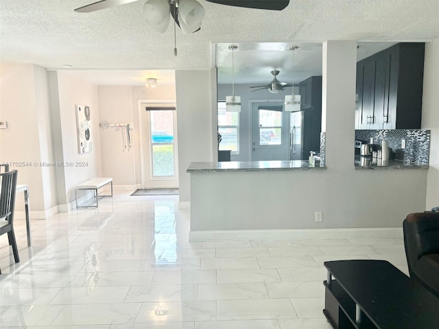 kitchen with backsplash, kitchen peninsula, stainless steel fridge, and a textured ceiling