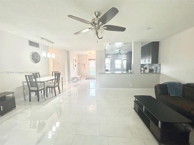 living room with a textured ceiling and ceiling fan