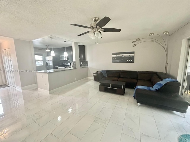 living room featuring ceiling fan and a textured ceiling