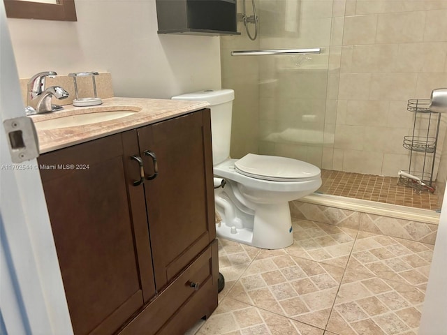 bathroom with an enclosed shower, vanity, toilet, and tile patterned flooring