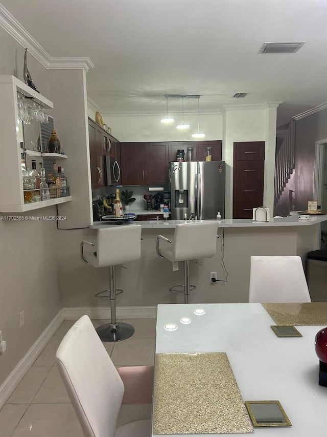 kitchen featuring kitchen peninsula, appliances with stainless steel finishes, ornamental molding, light tile patterned floors, and a breakfast bar area