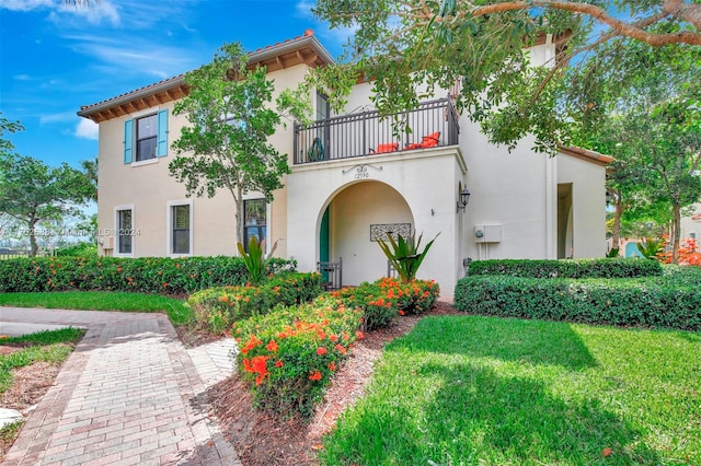 mediterranean / spanish-style home with a balcony and a front lawn