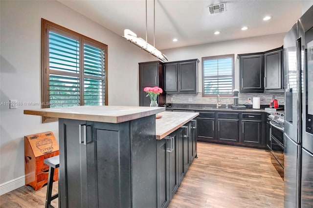 kitchen featuring a center island, tasteful backsplash, pendant lighting, a breakfast bar, and light wood-type flooring