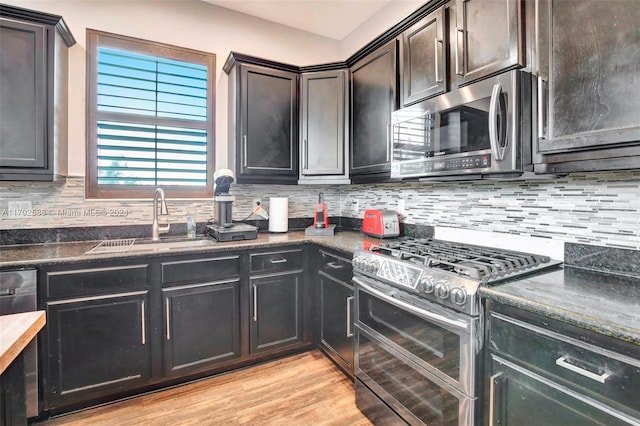 kitchen featuring dark brown cabinetry, sink, stainless steel appliances, tasteful backsplash, and light wood-type flooring