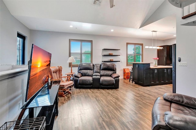 living room featuring light hardwood / wood-style floors, vaulted ceiling, and plenty of natural light