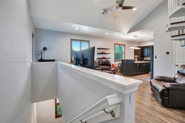 living room featuring ceiling fan, light hardwood / wood-style flooring, and lofted ceiling