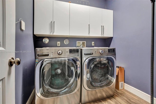 washroom with washing machine and dryer, light hardwood / wood-style flooring, and cabinets