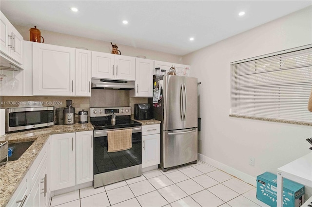 kitchen featuring light stone countertops, appliances with stainless steel finishes, white cabinetry, and light tile patterned flooring