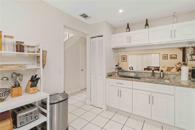 kitchen with light stone countertops, sink, and white cabinets