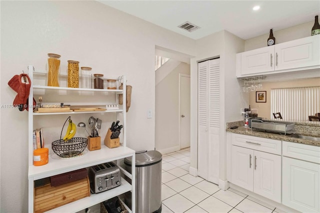 kitchen with light tile patterned flooring, white cabinetry, and stone counters