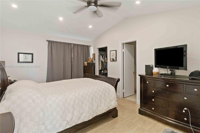 bedroom with vaulted ceiling, light hardwood / wood-style flooring, ceiling fan, a spacious closet, and a closet