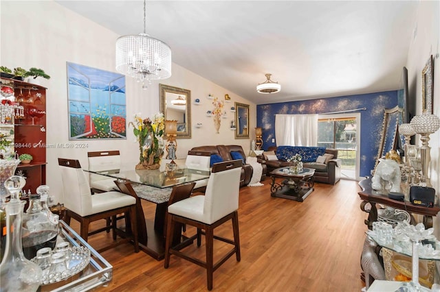 dining area featuring hardwood / wood-style floors, lofted ceiling, and an inviting chandelier