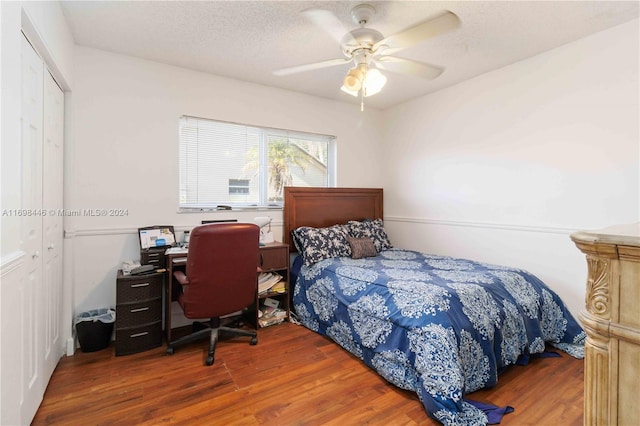 bedroom with a textured ceiling, a closet, dark hardwood / wood-style floors, and ceiling fan