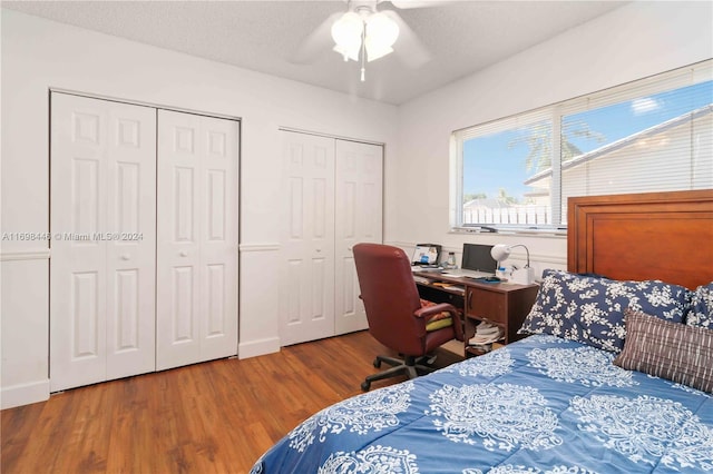 bedroom featuring multiple closets, ceiling fan, a textured ceiling, and hardwood / wood-style flooring