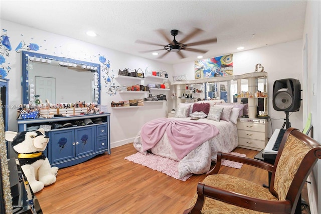 bedroom with ceiling fan, light hardwood / wood-style floors, and a textured ceiling