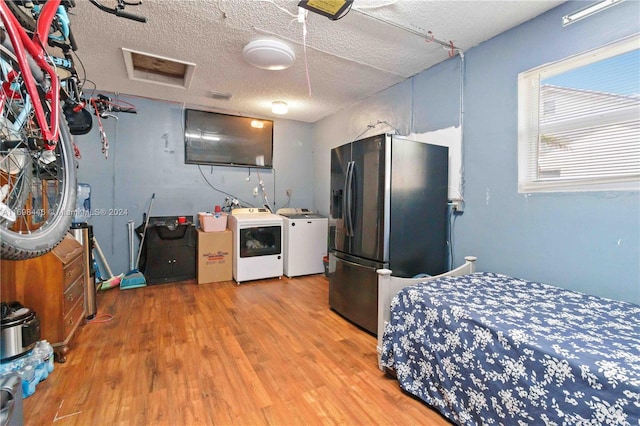 kitchen with stainless steel fridge with ice dispenser, washer and clothes dryer, wood-type flooring, and a textured ceiling