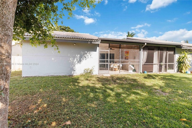 rear view of property featuring a yard and a sunroom