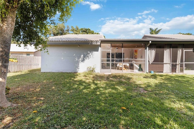 rear view of property featuring a yard, a patio area, and a sunroom