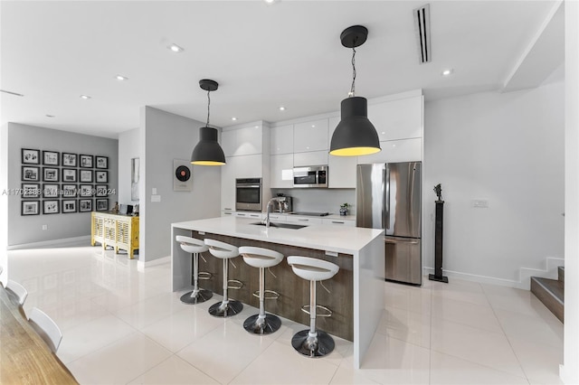 kitchen with white cabinetry, sink, pendant lighting, a center island with sink, and appliances with stainless steel finishes