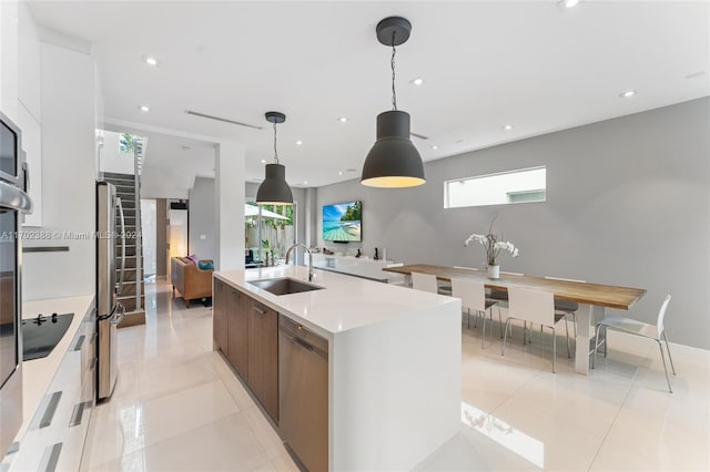 kitchen with sink, hanging light fixtures, an island with sink, white cabinets, and appliances with stainless steel finishes