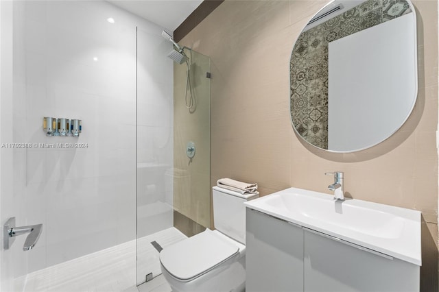 bathroom with a tile shower, vanity, and toilet