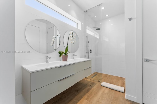 bathroom with hardwood / wood-style floors, vanity, and tiled shower