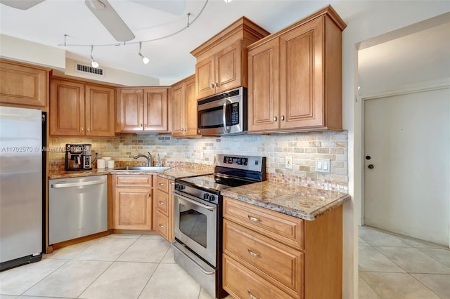 kitchen with sink, rail lighting, backsplash, light tile patterned floors, and appliances with stainless steel finishes