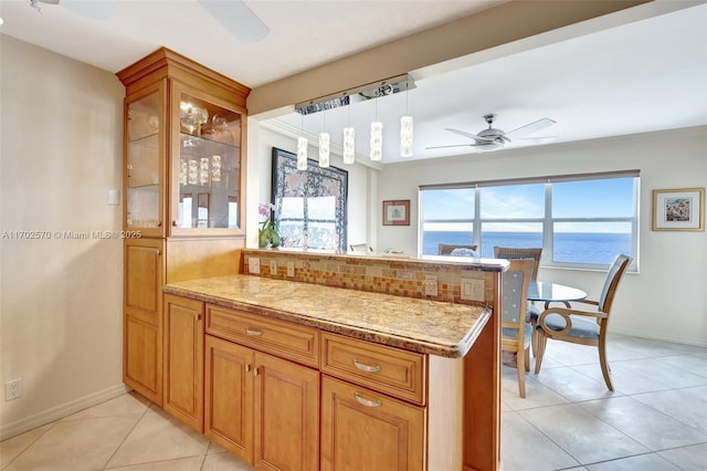 kitchen featuring kitchen peninsula, ceiling fan, light tile patterned floors, a water view, and hanging light fixtures