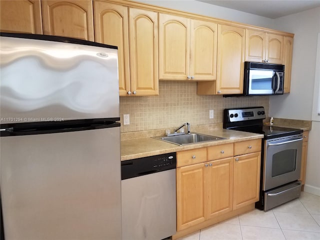 kitchen with sink, backsplash, light brown cabinetry, light tile patterned flooring, and appliances with stainless steel finishes