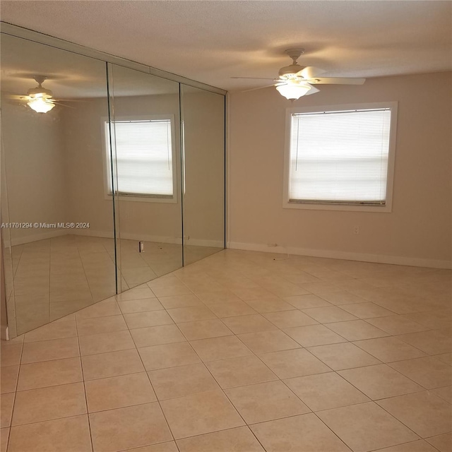 unfurnished bedroom featuring ceiling fan, light tile patterned floors, a textured ceiling, and a closet