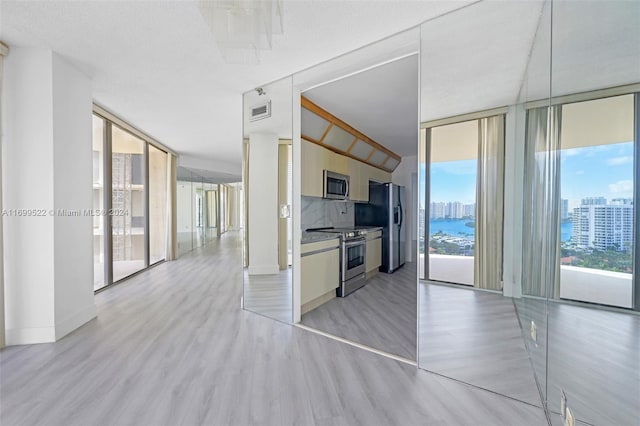 kitchen featuring plenty of natural light, expansive windows, light hardwood / wood-style flooring, and appliances with stainless steel finishes