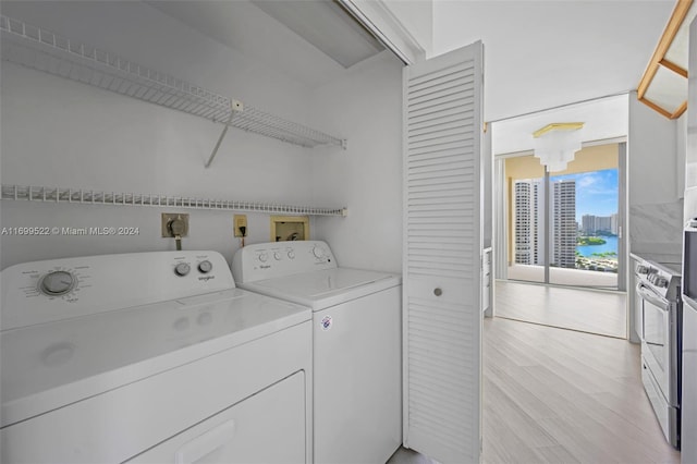 washroom featuring independent washer and dryer, a water view, and light hardwood / wood-style flooring