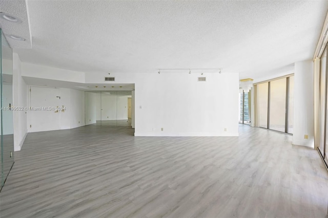 unfurnished living room with hardwood / wood-style floors, expansive windows, and a textured ceiling