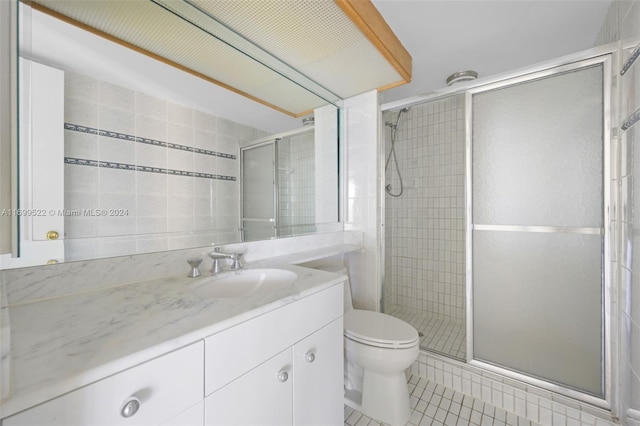 bathroom featuring tile patterned flooring, vanity, toilet, and walk in shower